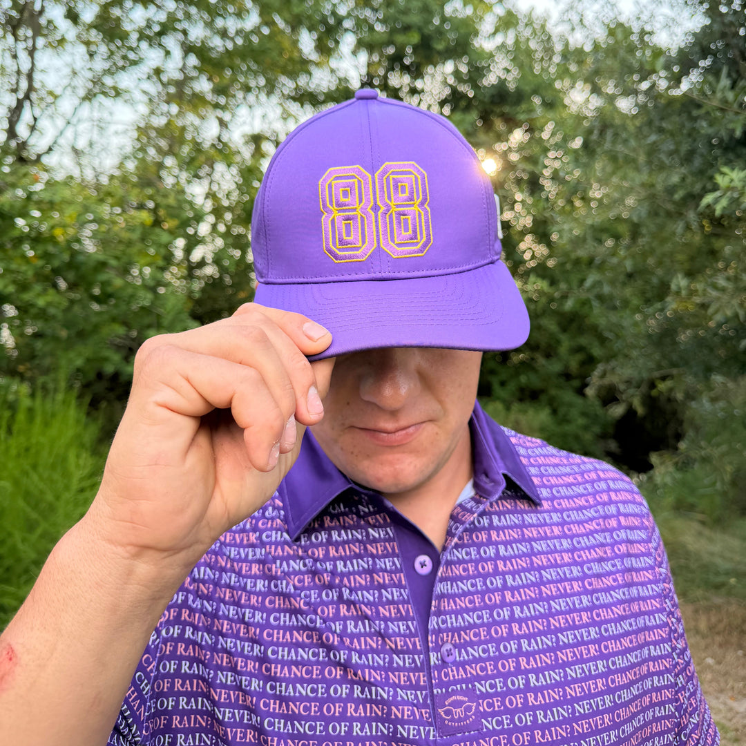 A man wearing a purple baseball cap with a gold &