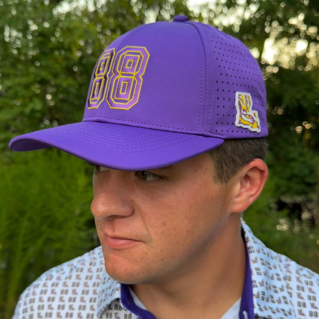 A man wearing a purple baseball cap with yellow and white &