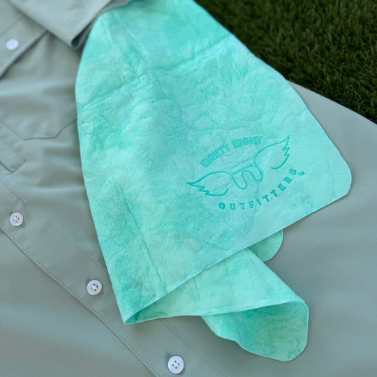 A mint green tie-dye bandana with a winged logo and the words &