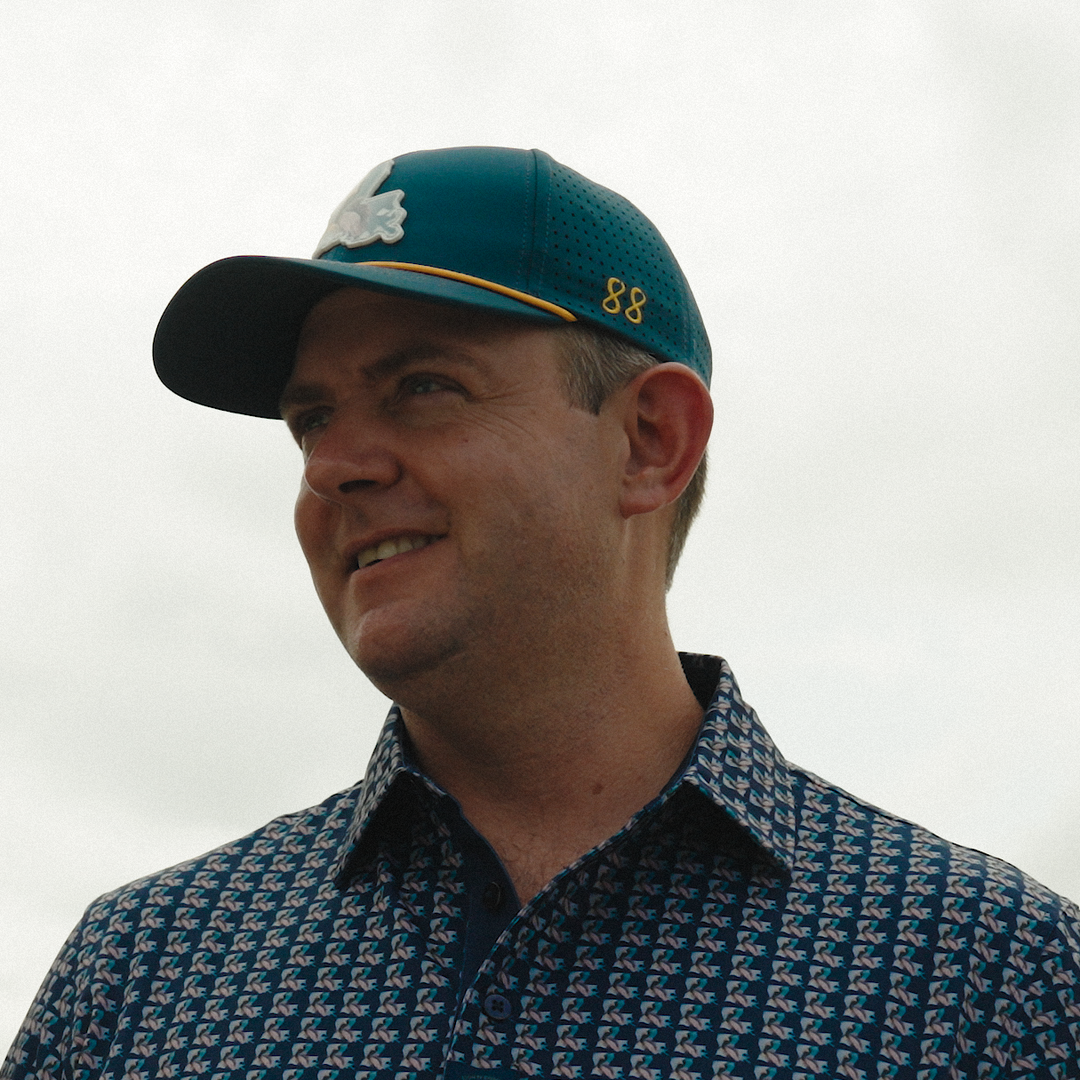 Man wearing a patterned shirt and cap with a blurred background