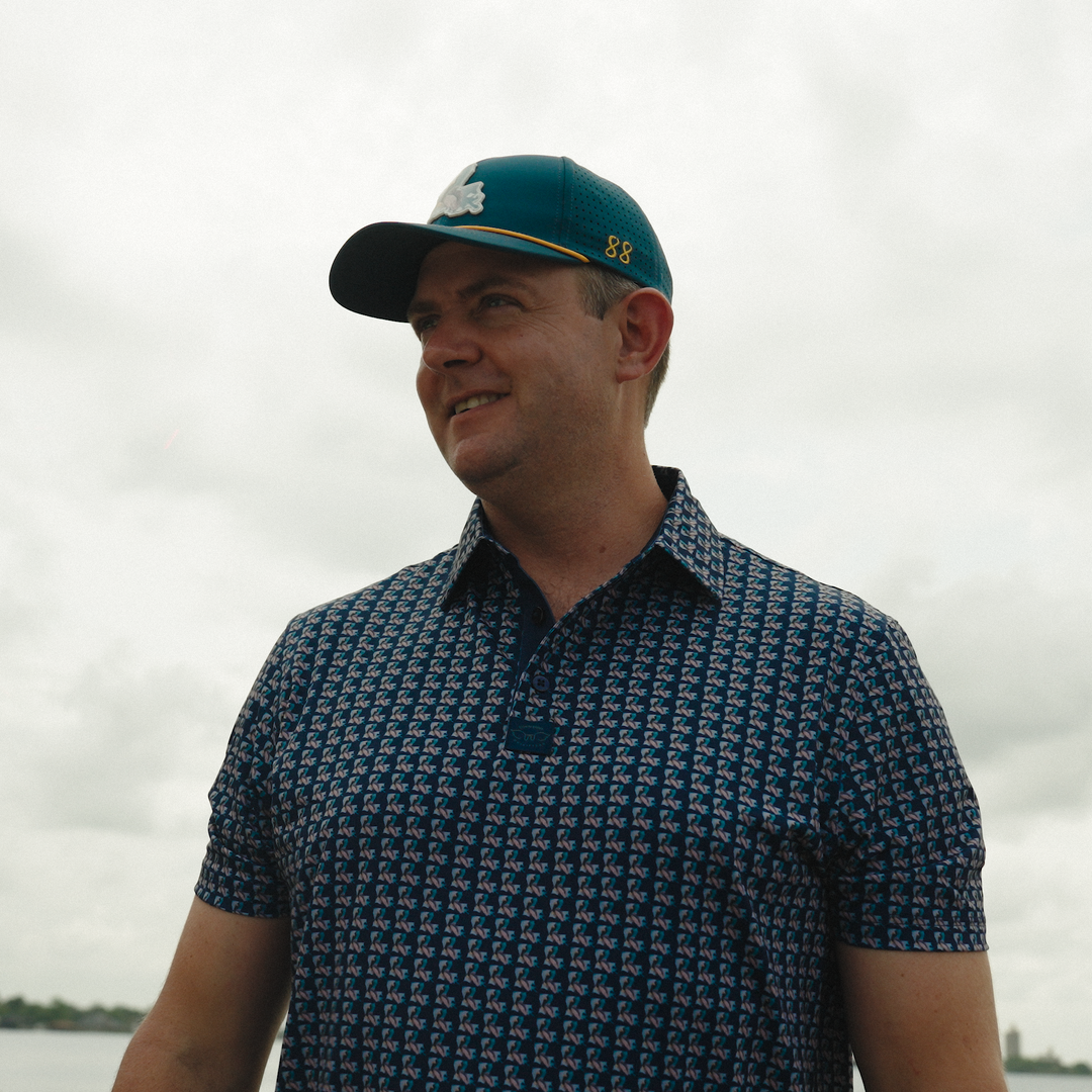 Man wearing a patterned shirt and cap with a blurred background