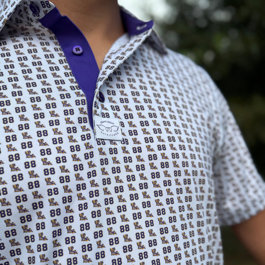 Close-up of a white short-sleeve polo shirt with a repeating brown and navy &