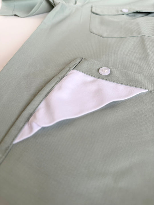 Close-up of a green jacket with a button and white lining on a light background