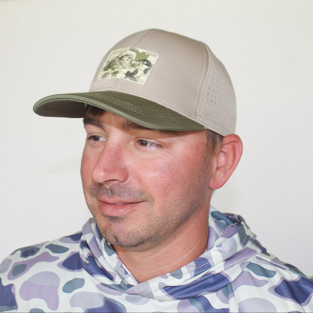 Man wearing a camouflage cap and patterned jacket against a plain background