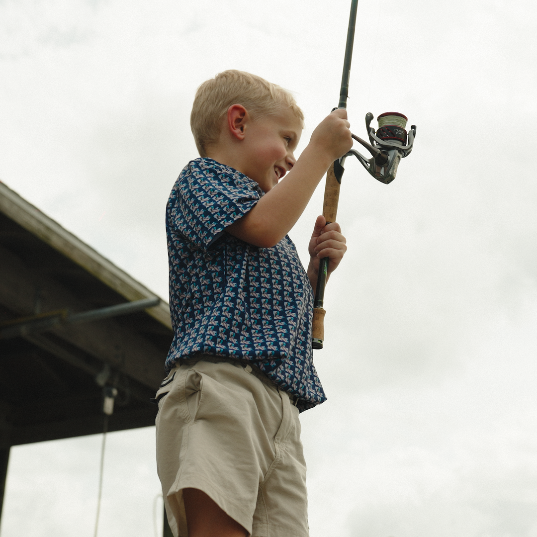 Child holding a fishing rod against a light background