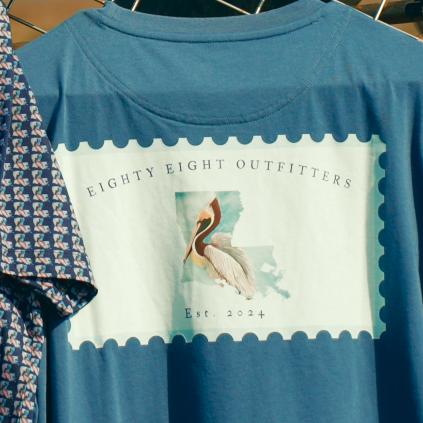 Blue patterned shirt, blue cap, and blue t-shirt with graphic design on a metal structure.