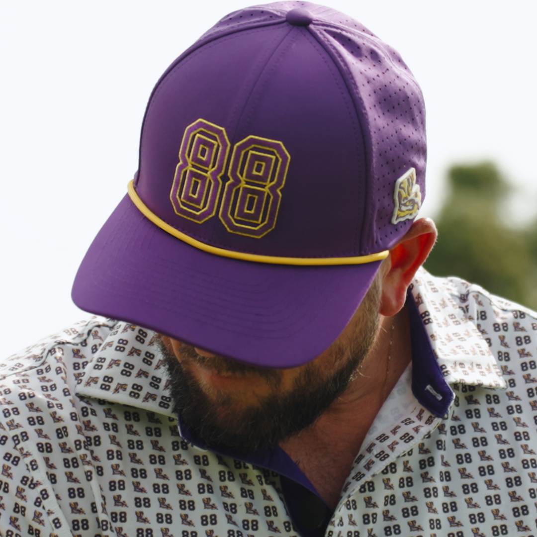 A man wearing a purple baseball cap with gold and black &