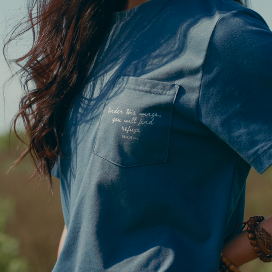 Blue shirt with text on a pocket against a blurred natural background
