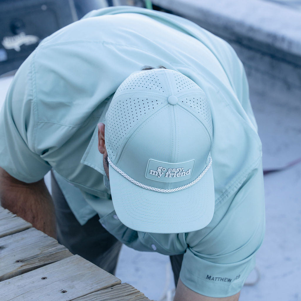 Person wearing a light blue shirt and cap on a dock