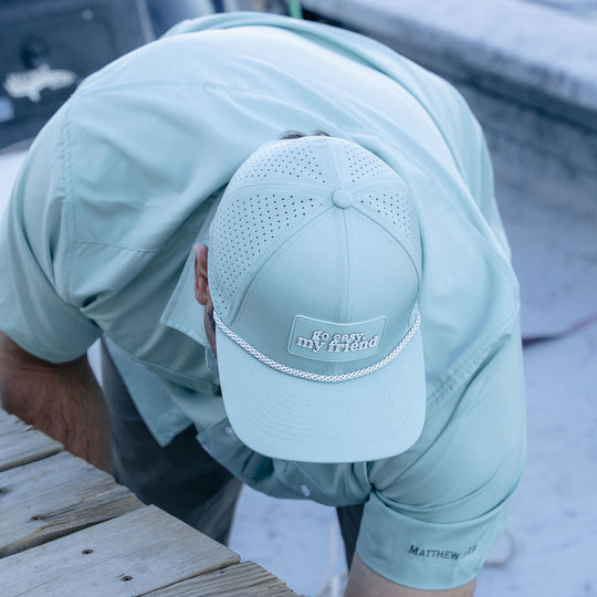 Person wearing a light blue shirt and cap on a dock