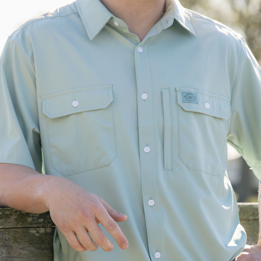 Light green short-sleeve shirt worn by a person, with a blurred natural background